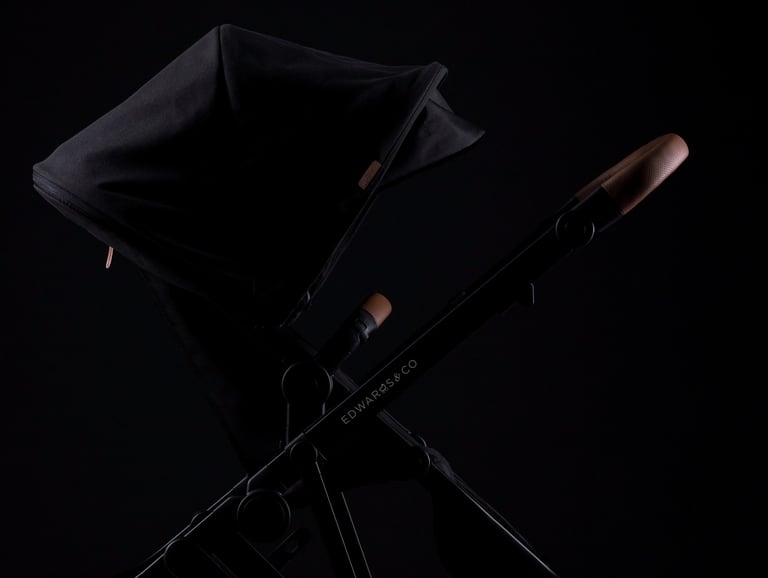 Product campaign photography - a baby stroller with brown leather handles on a black background