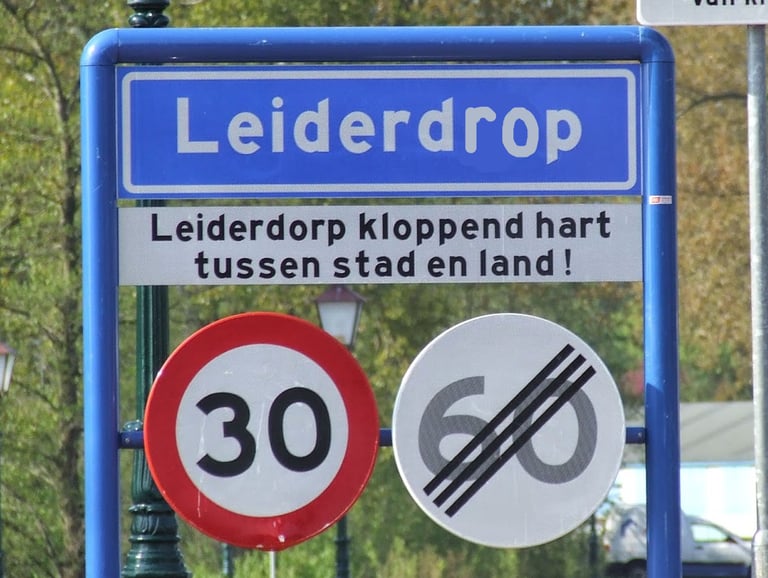 Blauw plaatsnaambord waarop 'Leiderdorp' is herschreven tot 'Leiderdrop', dat Jamie als kind las.