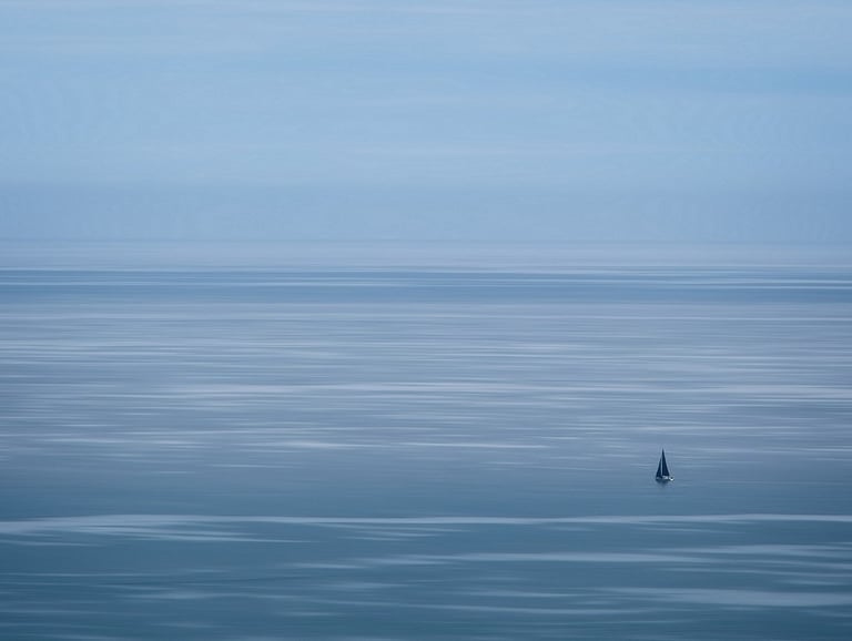 Small, lonely boat with black sails on a vast sea.