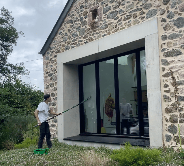 Nettoyage de grandes baies vitrées en cours avec mouilleur et raclette pour un résultat sans traces.