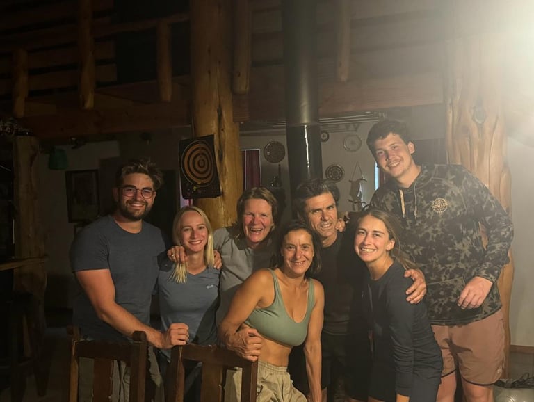 A group of seven people posing for a photo inside a wooden cabin.