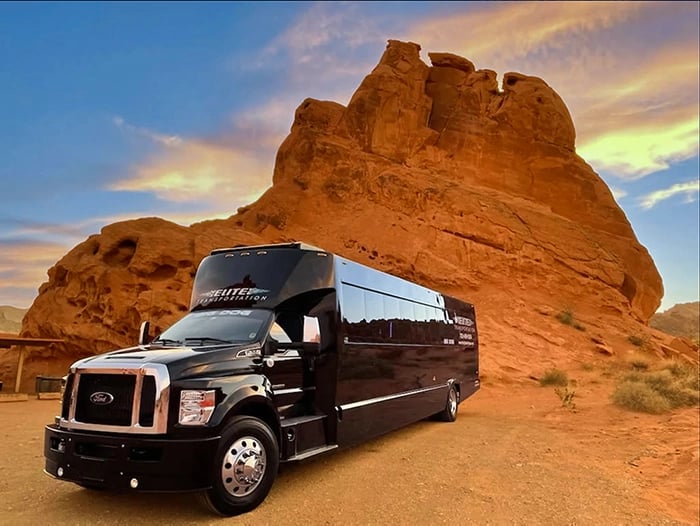 a black bus parked in front of a mountain
