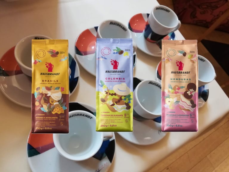 Confezioni Hausbrandt monorigine accanto a tazzine da espresso
