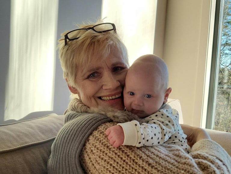a woman in a sweater and sunglasses is holding a baby