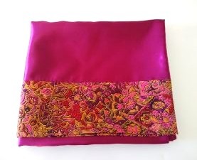 A burgundy pillowcase hemmed in a floral paisley trim on a white background.