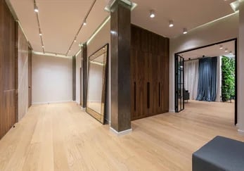 Modern luxury hallway with light oak hardwood flooring, floor-to-ceiling mirror, and wood paneling.