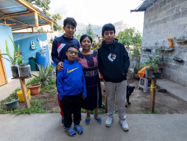 Guatemalan coffee-growing family standing together at their home in San Juan, Guatemala.