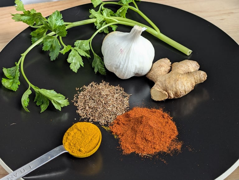 Fresh aromatics prepared for cooking, including ginger, garlic, spices and herbs