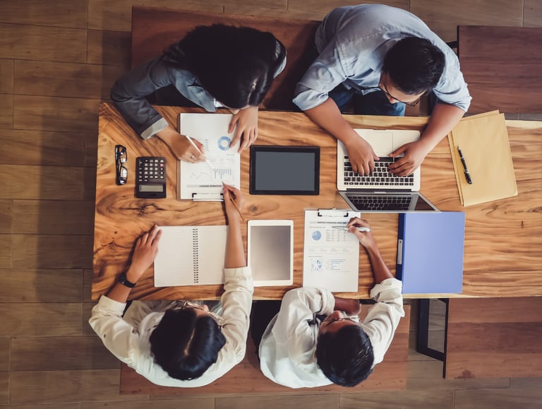 a group of people sitting at a table with laptops