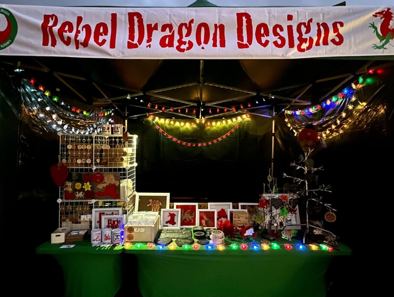 The Rebel Dragon Designs stall lit up with christmas and fairy lights at a Christmas market