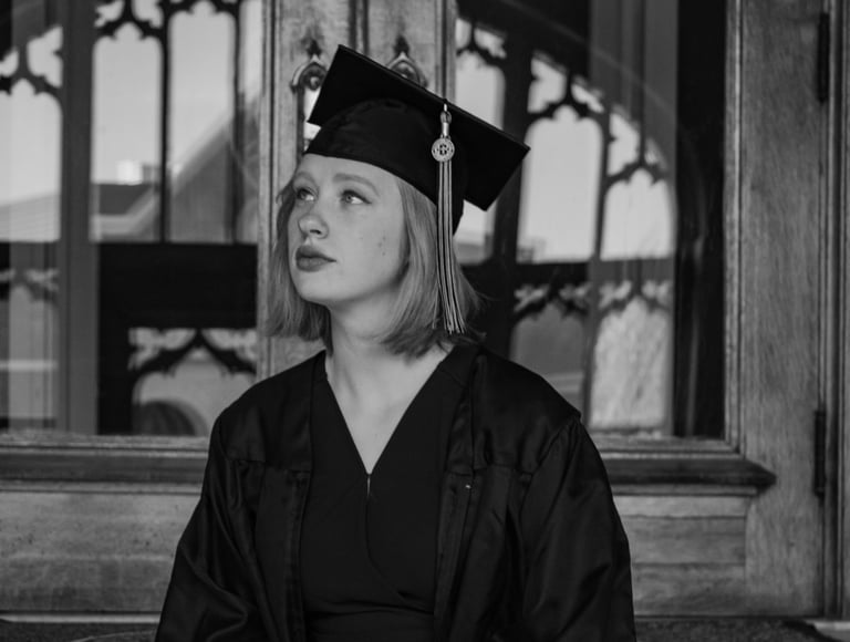 a woman in a graduation gown sitting on the steps