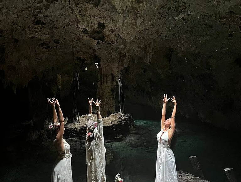 Three women in white dresses performing a sacred womb dance ritual in a cenote cave in Tulum, Mexico