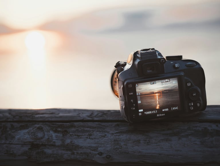 un appareil photo déposé sur une table de bois et positionné pour attendre le plus beau couché de soleil du lac