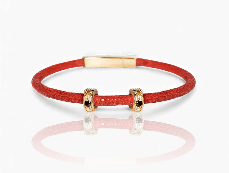 Red stingray leather bracelet featuring gold charms with black crystals.