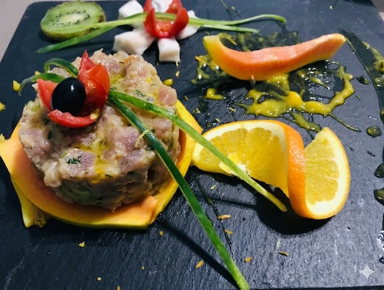 Elegante composizione di tartare di tonno con fettine di arancia, melograno e decorazioni di verdure