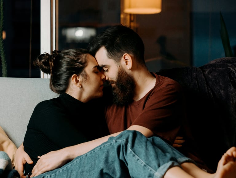 Ein Mann und eine Frau kuscheln verliebt am Sofa