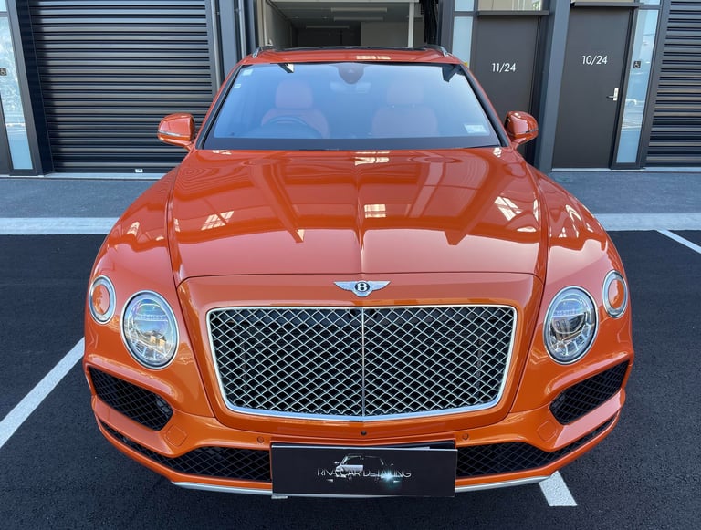 Front view of an orange Bentley Bentayga luxury SUV parked outside The Coating Lab