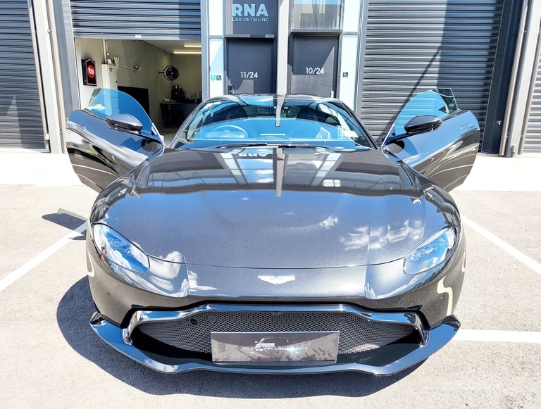 Black Aston Martin Vantage with swan-wing doors open parked outside The Coating Lab Auckland
