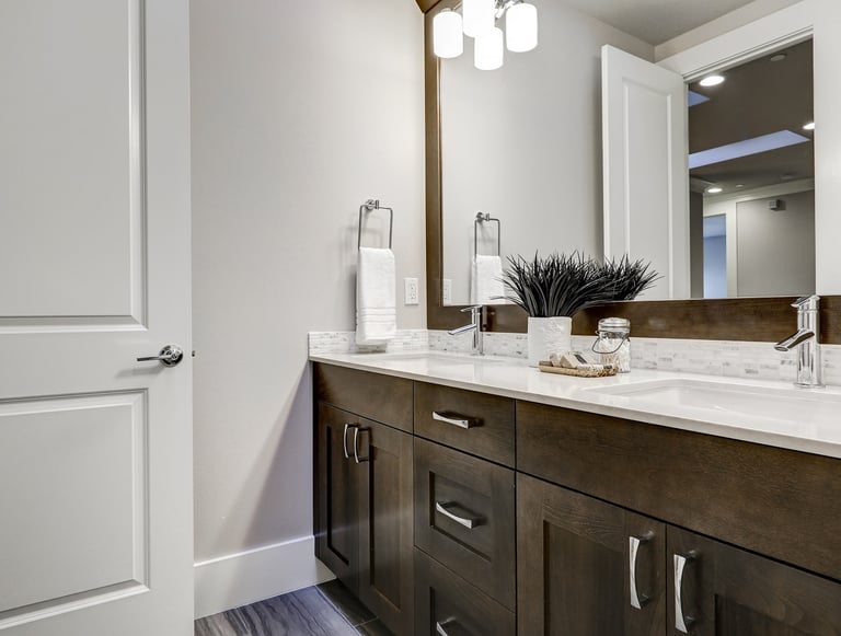 Modern bathroom remodel featuring a dark wood double vanity with white quartz countertops and large mirror.