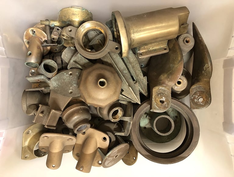 A bin full of various brass parts inside an assemblage artist's studio.