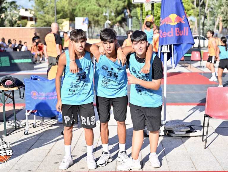 Three young basketball players in light blue jerseys pose at an outdoor 3x3 tournament.