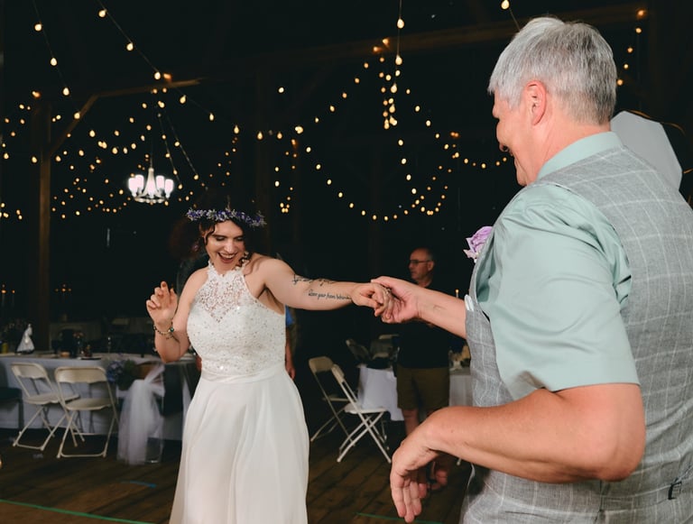 a bride and her father dancing at a wedding and having fun in a barn
