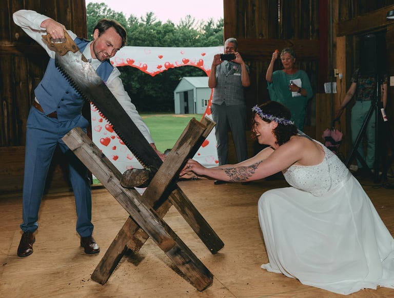 a groom and a bride cutting a piece of wood with a saw together