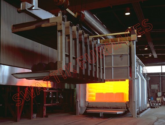 Industrial heat treatment furnace with open door showing glowing orange interior and loading mechanism.