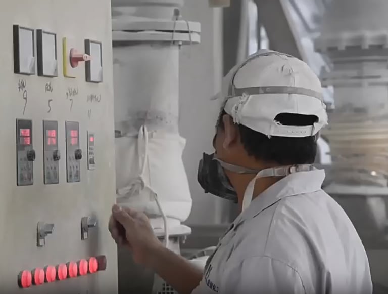 A man in a white uniform wearing a mask working in a production plant
