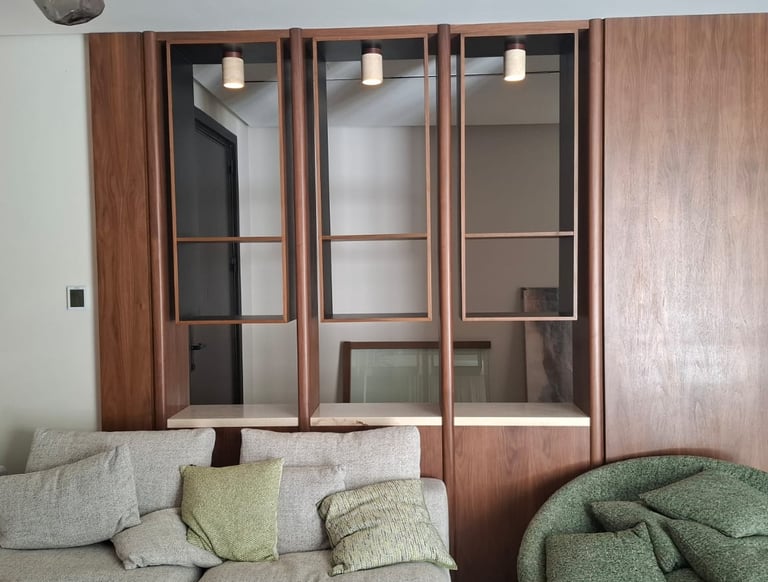 Modern living room with a custom wood wall unit, built-in shelving, and a grey sectional sofa.