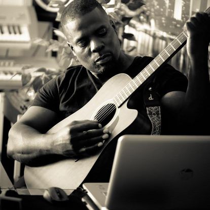 Dr. Marlon Ware sitting and playing a guitar