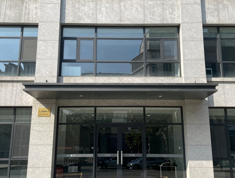 A glass door and window display the words 'Chilco Towers' with the number '710' above. A reflection partially obscures the view inside. A green leafy plant is prominently positioned on the left side of the image.