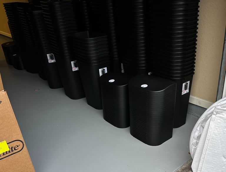 black trash cans stacked in a garage