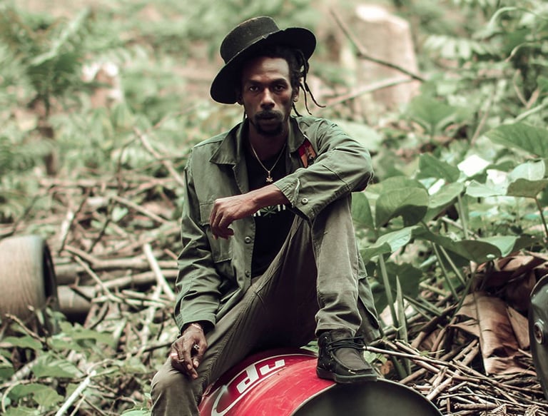 a man in a hat and a hat sitting on a barrel of oil