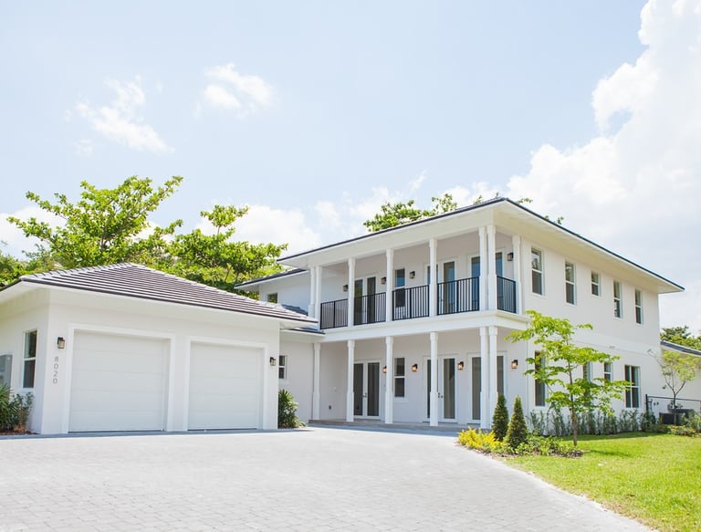 a white luxury home with a large driveway shown and a two door garage
