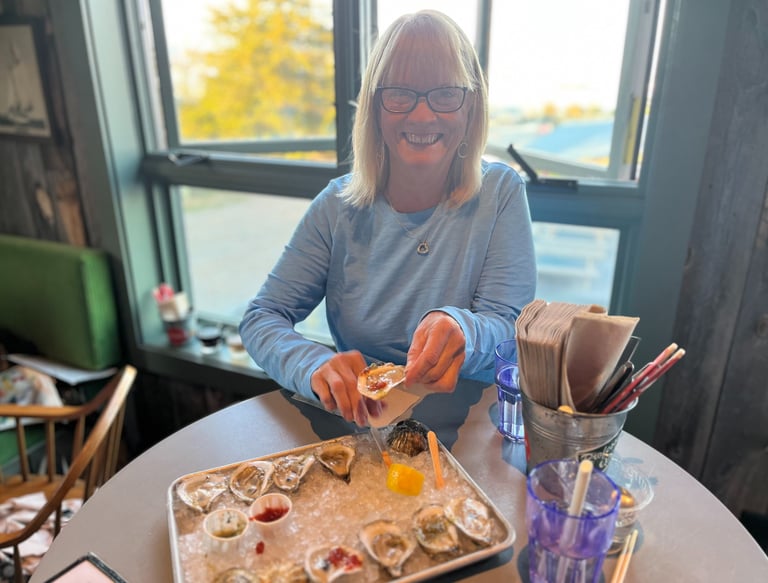 a woman in glasses and a blue shirt is holding a tray of oyster oysters