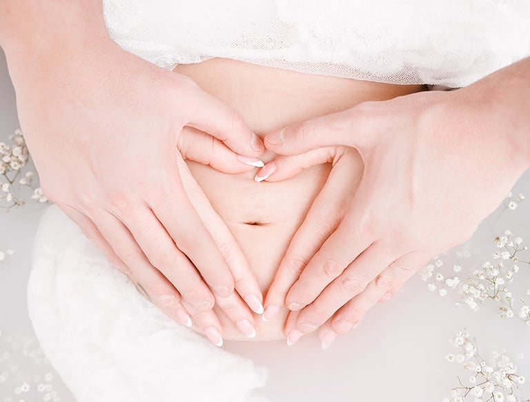 Photo grossesse bain de lait avec les mains en coeur sur le ventre