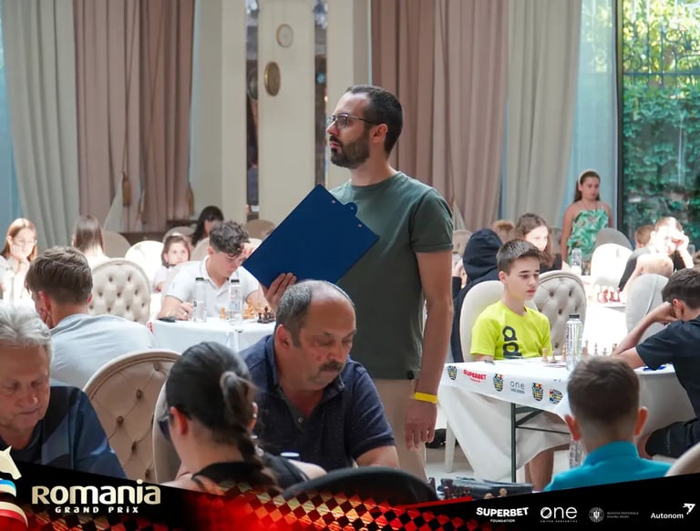 FIDE Arbiter Vlad Ghita holding a clipboard in the middle of a tournament hall and watching games