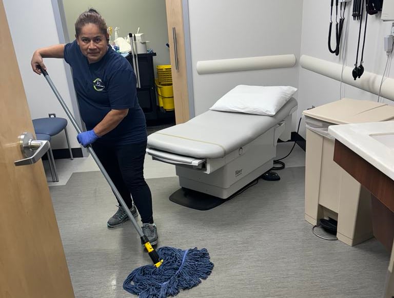 a woman in a hospital room cleaning a floor