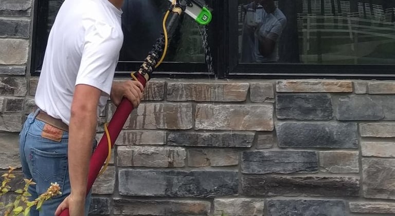 A man cleaning windows for a luxury home with a five stage filtration water pool