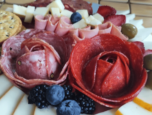 A beautifully crafted flower of salami and pepperoni on a gourmet charcuterie board featuring an ass