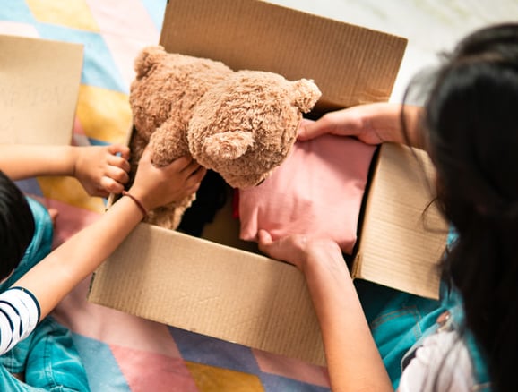une femme maman et un enfant petit garçon emballe dans un carton un ours en peluche