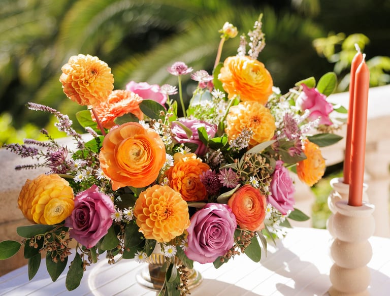 composition florale teintes vives et bougies oranges