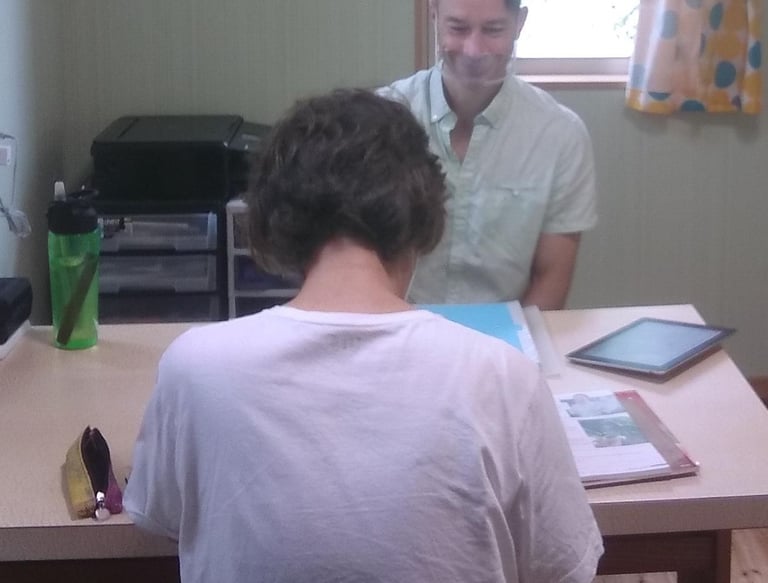 man sitting at table teaching English to older woman