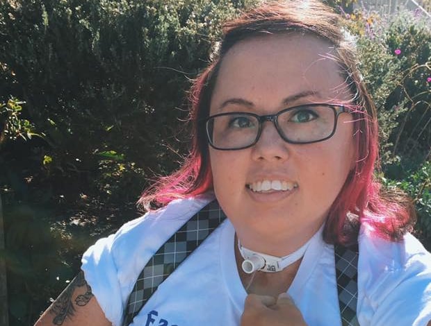 Photo of Stacey with suspenders, pink hair, tee shirt that says "Famous witches", with tattoos showing.