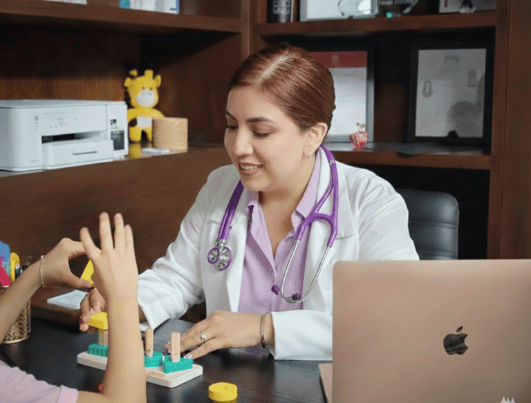 Dra Isis Pediatra con bata blanca utilizando bloques de madera durante una evaluación de un niño