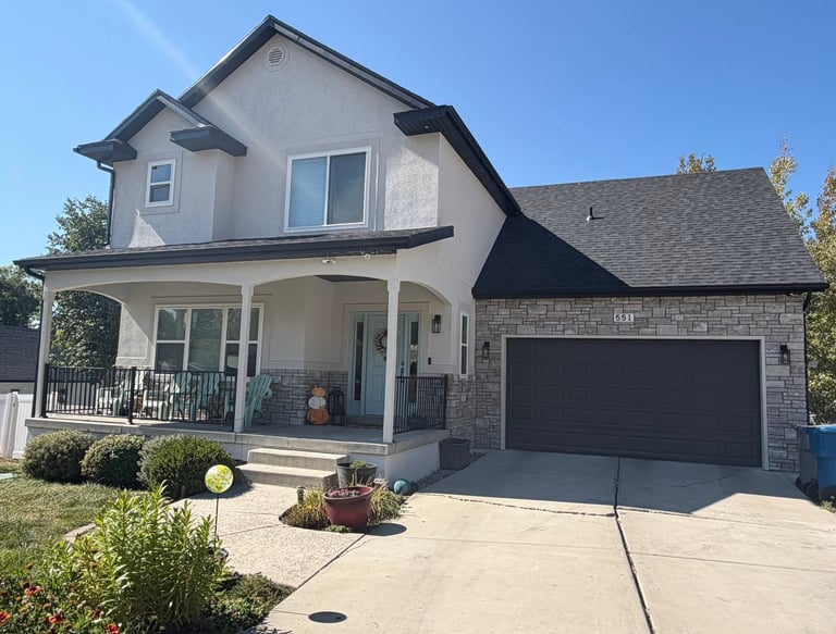 after exterior remodel house is now cream-colored stucco with natural stone veneer in light to medium gray tones.