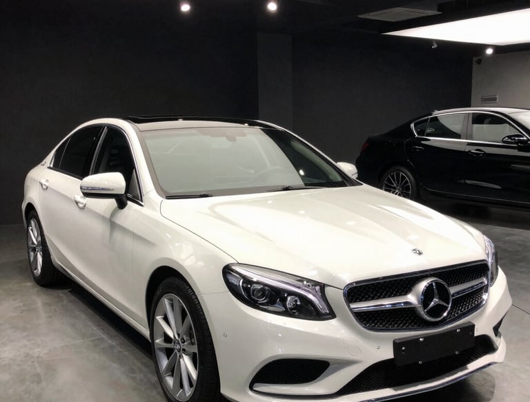 A sleek black luxury car being expertly parked by a sharply dressed valet at a grand hotel entrance.