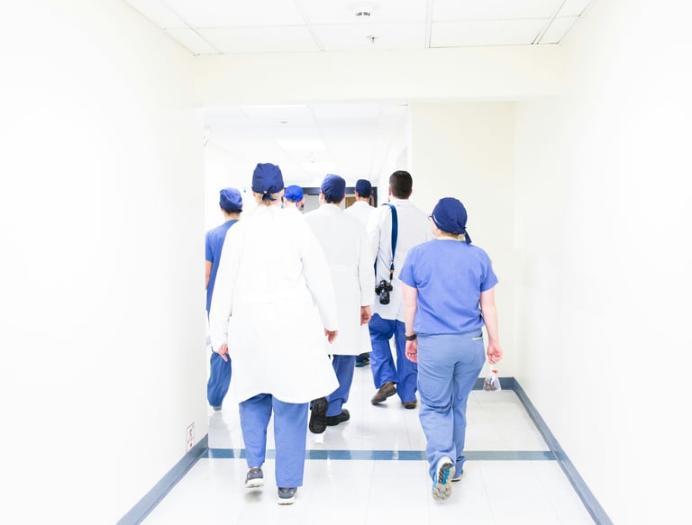 group of doctors and nurses in scrubs walking down a hospital corridor to their OET exam.