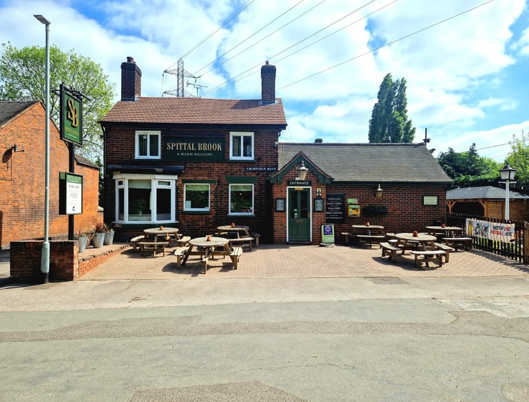 a restaurant with tables and benches in front of a brick building